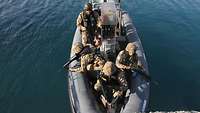 Fünf Soldaten sitzen im Speedboot.