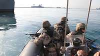 Soldaten fahren im Speedboot durch den Hafen.