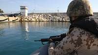 Soldat beobachtet den Hafen vom Boot aus
