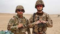 Ein deutscher und ein US-amerikanischer Soldat stehen mit Helm und Schutzweste gemeinsam in der Wüste