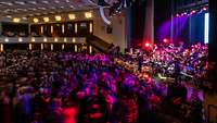 Ein Ballsaal mit tanzendem Menschen und einer Band auf der Bühne