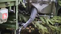 Ein Soldat greift mit einem Gummiarm aus einem Radpanzer in Litauen