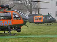 Zwei Hubschrauber stehen leicht versetzt hintereinander auf einer Wiese.