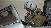 Ein Pilot sitzt in einem Kampfjet der Bundeswehr und blickt offenbar auf eine Checkliste