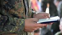 Soldat mit einem Gesangbuch beim Friedensgottesdienst