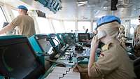Eine Soldatin auf der Brücke eines Schiffes nimmt Funkkontakt zu einem zu kontrollierenden Schiff auf