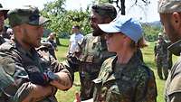 Eine Soldatin mit einem hellblauen Basecap spricht mit Soldaten.