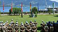 Soldaten mit blauen Basecaps sind zur Eröffnung einer Ausbildungsreihe auf grünem Rasen angetreten.