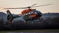 Ein Hubschrauber mit orangefarbenen Aufklebern steigt auf.