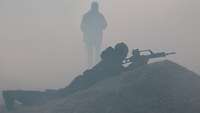 Ein Soldat liegt mit einem Gewehr im Nebel