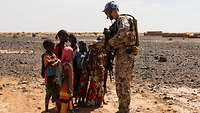 Eine kleine Gruppe malischer Kinder steht vor einem Soldaten und begrüßt diesen mit Handschlag