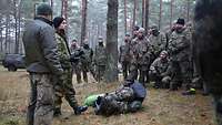 Eine Gruppe Soldaten steht im Wald und hört einem Norweger zu