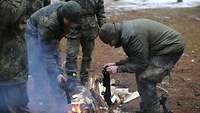 Soldaten trocknen ihre nassen Strümpfe über einem Feuer