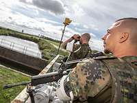 Ein Soldat beobachtet durch das Doppelfernrohr, einer beobachtet den Zaun