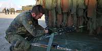 Ein Soldat verzurrt ein Fahrzeug auf der Ladepritsche eines Lkw 