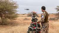 Ein Soldat steht vor einem Weihnachtsbaum