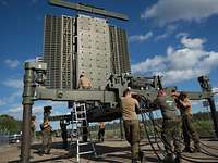 Soldaten befestigen Kabel und anderes an dem Radar, das sie aufbauen.