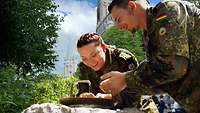 Eine Soldatinn und ein Soldat schöpfen Lourdes-Wasser