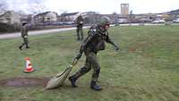 Ein Soldat mit Schutzweste und Helm zieht einen Sack