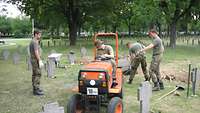 Vier Bundeswehrsoldaten bei der Arbeit auf einer Kriegsgräberstätte.