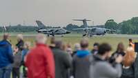 Besucher beobachten zwei Flugzeuge auf der Rollbahn