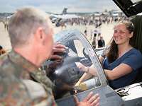 Ein Soldat spricht mit einer Frau, die im Cockpit eines Flugzeuges sitzt