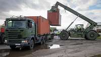 Szene einer Verladung. Container wird auf einen LKW geladen.