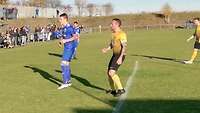 Zwei Fußballspieler in gelben beziehungsweise blauen Trikots stehen in Erwartung eines kommenden Ballesauf einem Kunstrasenplatz