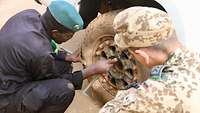 Ein malischer Soldat wechselt einen Reifen, während der Ausbilder dabei zu schaut und nützliche Tipps vermittelt