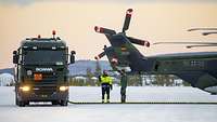 Ein Tankfahrzeug steht neben einem Hubschrauber. Beide sind verbunden mit einem Kraftstoffschlauch.