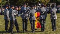 Soldaten sind um eine Deutschlandflagge herum angetreten, auf die einige jeweils eine Hand legen.