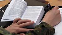 Ein Soldat studiert das Soldatengesetz und macht sich Notizen zum Thema Gehorsam.