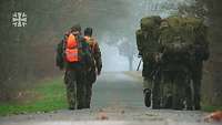 Soldaten marschieren auf einem Waldweg.