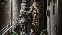 Ein amerikanischer und ein deutscher Soldat überprüfen gegenseitig ihre ABC-Schutzkleidung