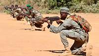 Eine Gruppe malischer Soldaten kniend im roten Sand mit den Sturmgewehren im Anschlag