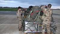 Zwei Soldaten sichern Taschen und Transportkisten auf einer Lufttransportpalette