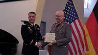 Ein amerikanischer hoher Offizier übereicht die Urkunde von der deutschen und amerikanischen Flagge an Prof. Dr. Teifke