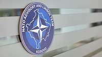 Blaues Wappen mit der Aufschrift Nato Advisory and Liaison Team Kosovo