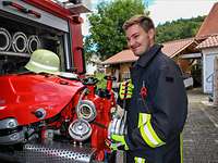 Gabriel steht am Löschfahrzeug der Freiwilligen Feuerwehr in seinem Heimatort.