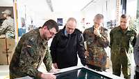 4 Soldaten stehen vor einem Multimedia-Tisch, dessen Tischplatte aus einem großen Touchdisplay besteht 
