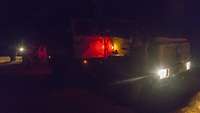 Ein Soldat und der Sprachmittler gehen im Dunkeln auf ein Fahrzeug vom Typ Dingo 2 zu