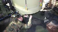 Ein Soldat schraubt an einem Metallbehälter