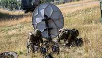 Zwei Soldaten bauen eine Satellittenschüssel auf