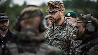 Fünf Soldaten und ein ziviler Mechaniker stehen im Halbkreis auf dem Übungsplatz.