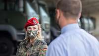Eine Soldatin mit Maske redet mit einem zivil gekleideten Mann