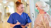 Krankenschwester und eine Kollegin mit Mundschutz im Gespräch.
