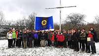 Abschlussfoto der Pilgergruppe aus Nordrhein-Westfalen mit einer blauen Fahne am Birkenkreuz