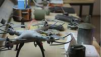 Eine Drohne steht auf einem Tisch, im Hintergrund befinden sich viele weitere technische Gerätschaften