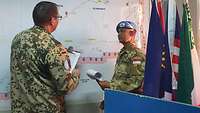 Zwei Soldaten stehen vor einer Landkarte und beraten sich