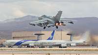 Ein Tornado startet mit Nachbrenner. Im Hintergrund stehen zwei AWACS der NATO, die ebenfalls an Red Flag teilnehmen